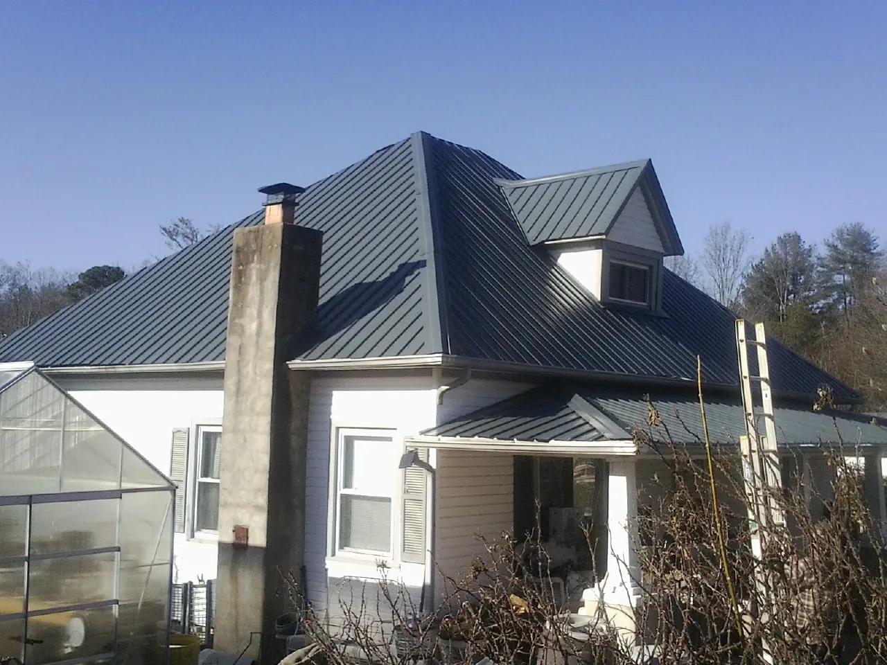 Dark blue standing seam metal roof on a white farmhouse with dormer — Slate & Tile Roof Repair by Roofing Brothers in Stone Park