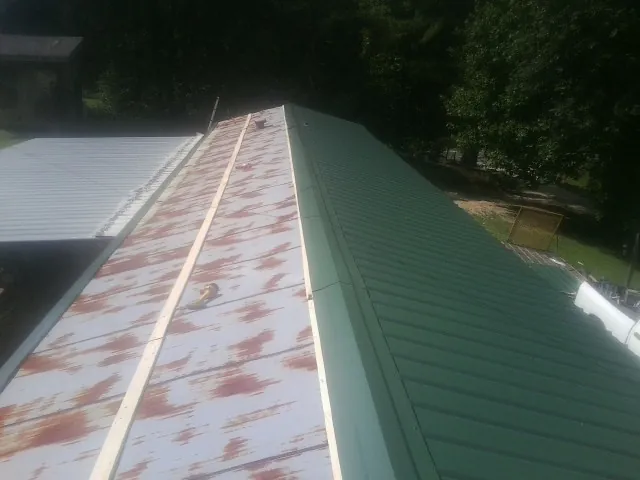 Old rusted panels beside newly installed green metal roofing — Wind Damage Roof Repair by Roofing Brothers in Stone Park