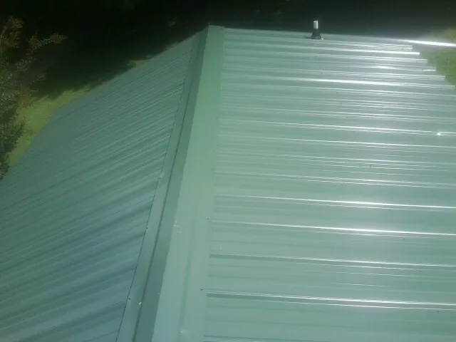 New green metal panels meeting at the ridge of a roof — Flat Roof Repair work by our crew in Stone Park