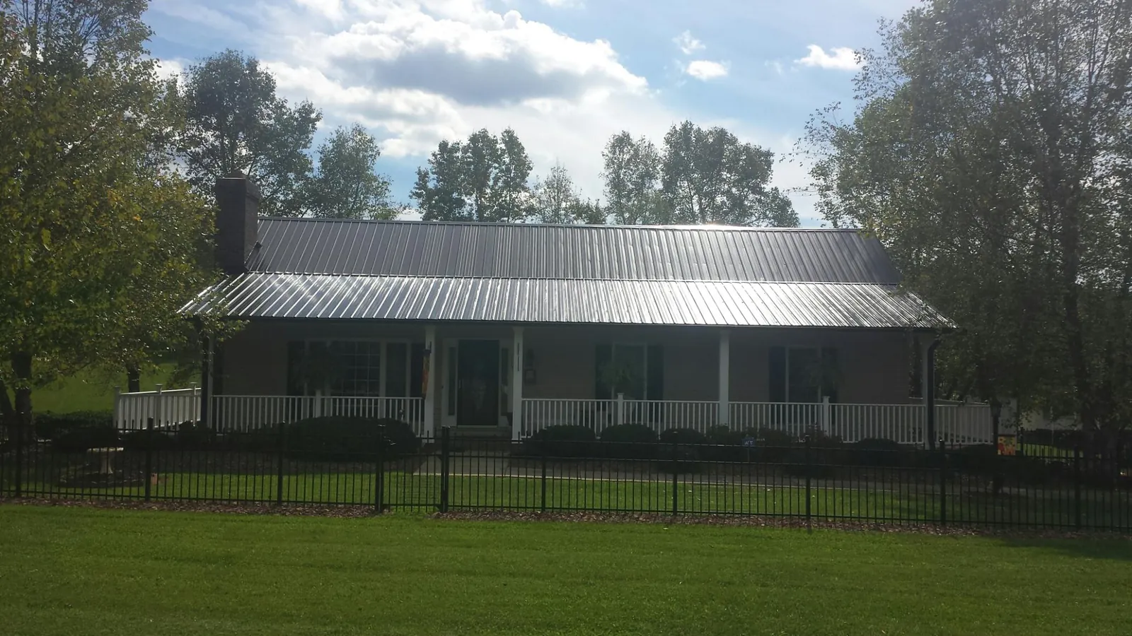 Gray metal roof on a brick ranch with a full width front porch — Gutter Guard Installation work by our crew in Stone Park