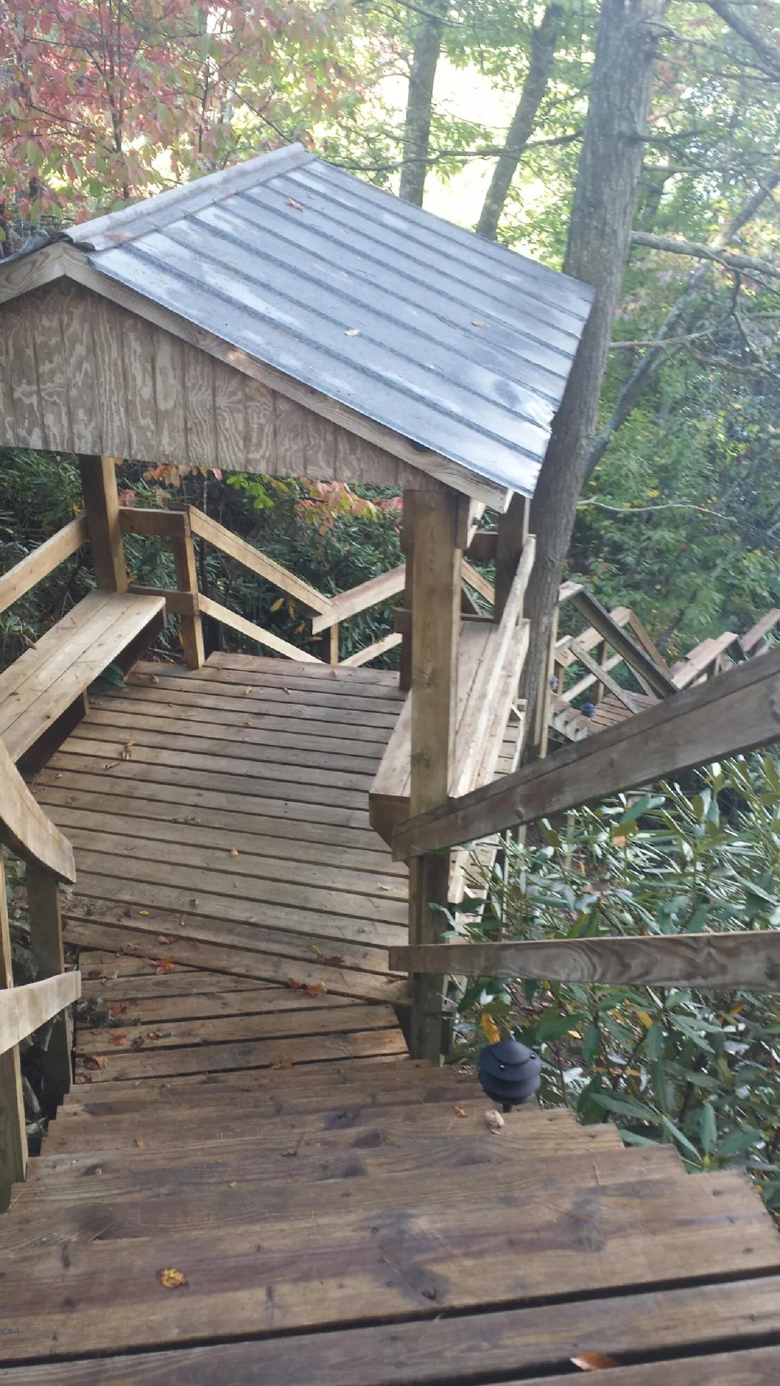 Metal roofed shelter over wooden steps on a wooded walkway — Skylight Repair & Installation work by our crew in Stone Park