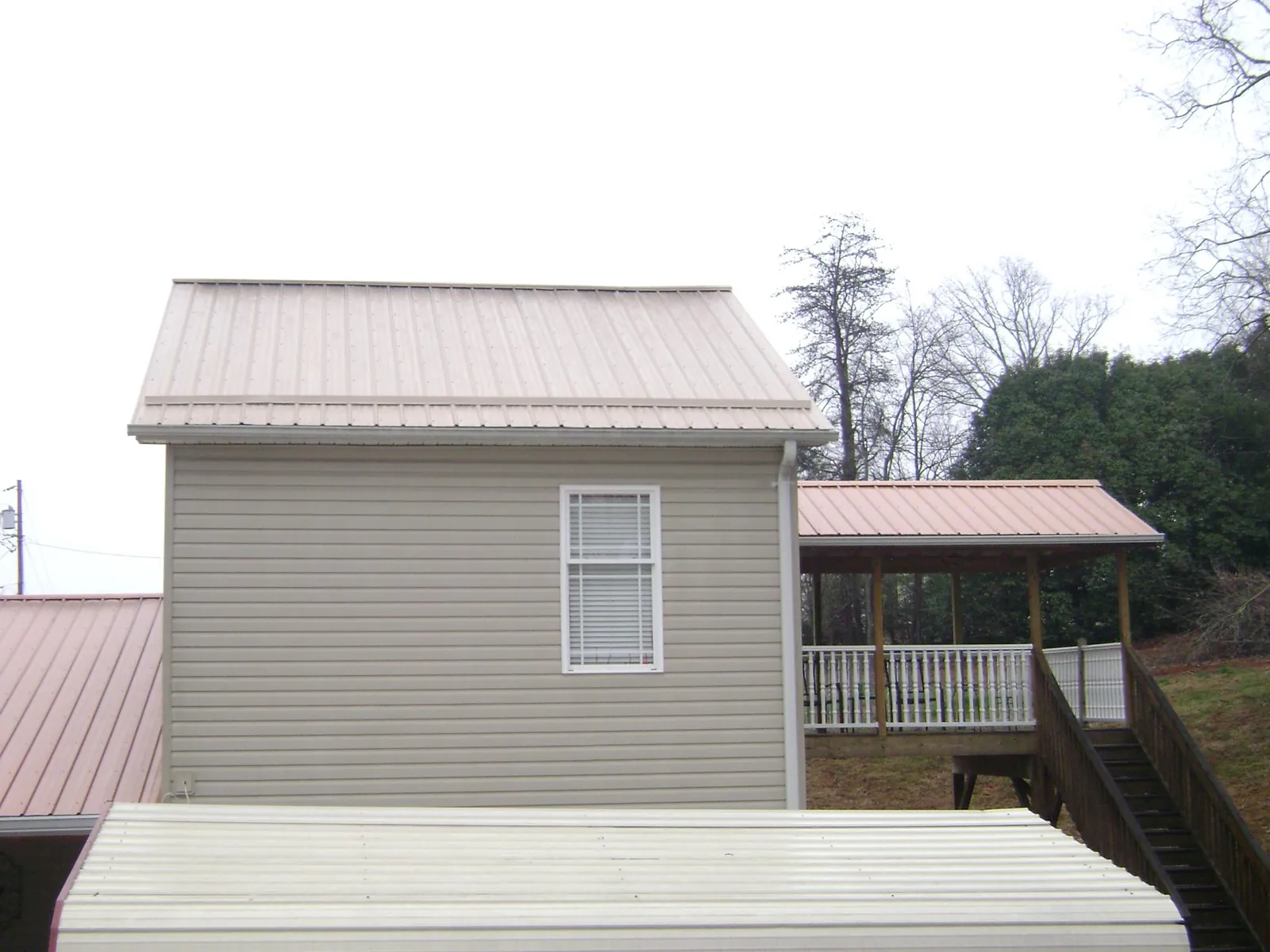 Tan metal roofs on a two story addition and attached porch, from a Roof Replacement job in Stone Park