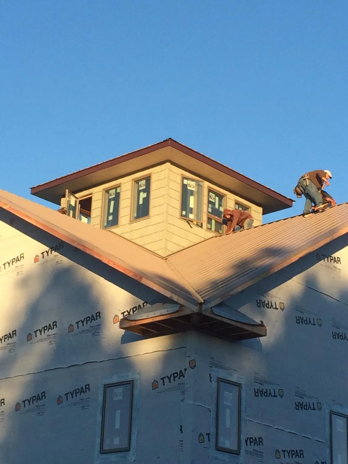 Roofers working around a rooftop cupola on a new metal roof at sunset — Roof Waterproofing in Stone Park by Roofing Brothers